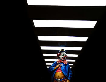 tunnel, creepy clown, statue, bright lights, dramatic contrast, clown statue, tunnel lights, eerie clown, clown in tunnel, clown under lights