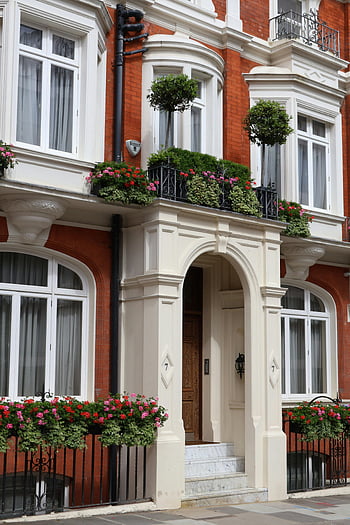 traditional tenement house, London architecture, colorful flowers, balcony flowers, classic architecture, elegant facade, London building, brick facade, white trim, arched windows, decorative balconies