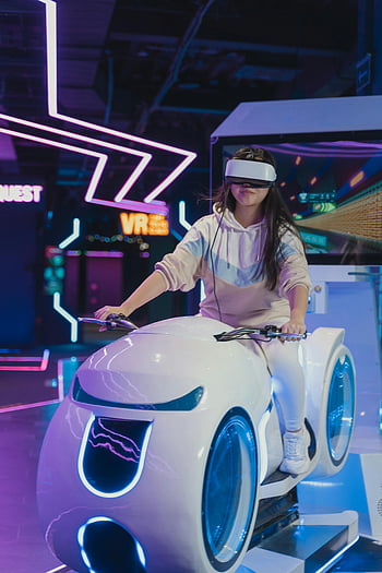 kvinne, virtuell virkelighet, vr hodesett, futuristisk simulator, neonopplyst miljø, gaming, Interaktiv opplevelse, teknologi, underholdning, ridesimulator, oppslukende erfaring