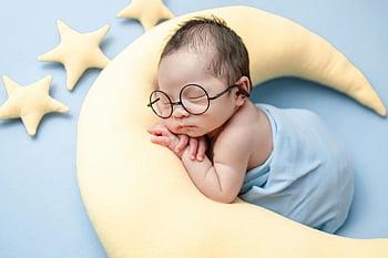 newborn photoshoot, sleeping newborn, crescent moon pillow, blue blanket, baby glasses, charming newborn, baby photography, newborn baby, baby props, star pillows, baby portrait