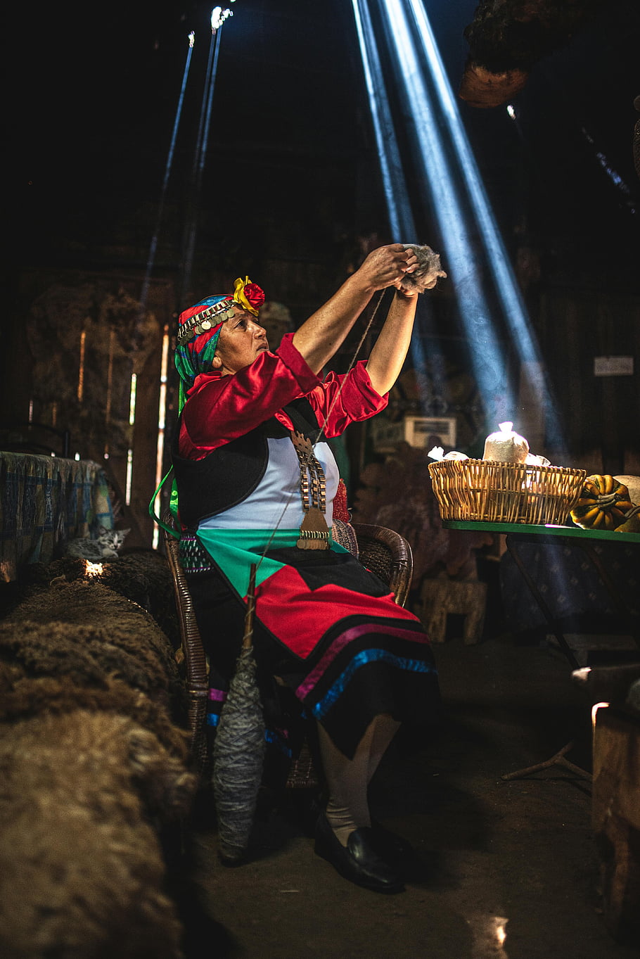 woman working with yarn, indigenous woman, colorful attire, Araucanía, Chile, sunbeams indoors, traditional craft, weaving, cultural heritage, artisan, yarn work