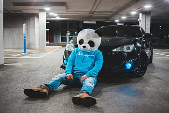 panda costume, man in panda mask, black car, illuminated parking garage, casual sitting, panda head, parking garage, panda mask, blue hoodie, champion hoodie, car in garage