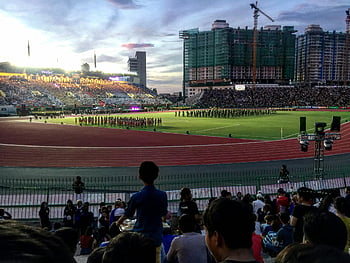 Cambodian stadium, football player team, evening sports event, crowd watching, lively sports event, football field, stadium crowd, evening stadium, sports crowd, Cambodian sports, football team