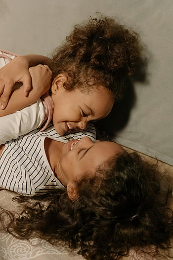 sibling hug, black sisters, cozy indoor, warmth, happiness, young girls, laughing, curly hair, family bond, sisterly love, playful moment