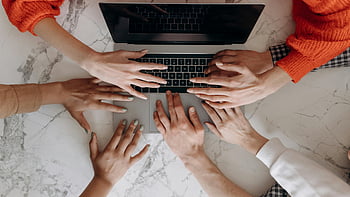 group collaboration, hands on laptop, overhead view, diverse group, working together, team cooperation, laptop keyboard, teamwork, group project, office setting, collaborative work