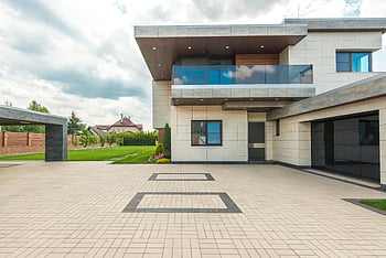 modern design building, concrete tiles, sleek design, large driveway, lush greenery, stylish modern house, contemporary architecture, exterior design, modern home, green landscaping, driveway design
