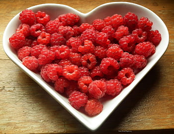 red berries, raspberries, heart-shaped bowl, wooden surface, vibrant red, food themes, health themes, fresh raspberries, healthy eating, heart bowl, red fruit