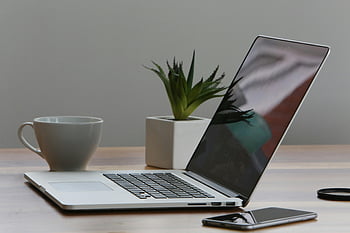silver laptop, white cup, minimalist desk, home office, modern work environment, smartphone, plant, wooden table, clean workspace, productivity setup, office decor