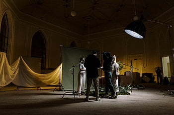 dark photo, people on stage, photography crew, setting up lighting, indoor photo shoot, stage setup, lighting equipment, indoor photography, photo shoot preparation, stage lighting, background setup