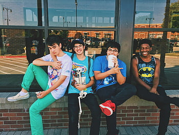 four men, sitting on platform, teenage friends, outdoors, smiling, having fun, group photo, casual clothing, brick wall, urban setting, social gathering