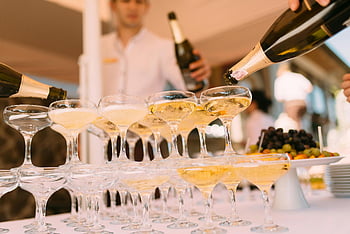 champagne, cocktail glasses, pouring liquor, festive celebration, outdoor event, elegant pouring, champagne glasses, celebration drinks, outdoor party, champagne pyramid, festive drinks