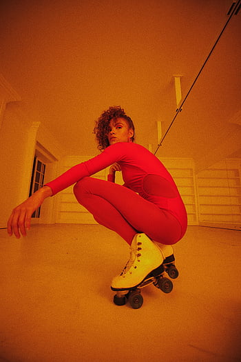 žena, kolečkové brusle, zářivě červený outfit, krčí se, uvnitř, energie, póza, móda, skate styl, fotografování v interiéru, zářivé barvy