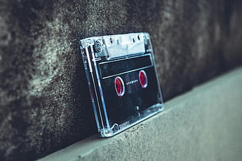 kazetová páska, Vintage zvuk, Nostalgická technologie, betonový povrch, detailní fotografie, černá a šedá, opřel se o zeď, Retro hudba, audiokazeta, Vintage kazeta, Nostalgický zvuk