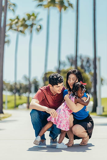 happy family, hugging, joyful family, bonding time, outdoors, heartwarming hug, palm tree background, family photo, outdoor family, family love, family moment