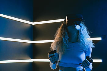 realitas virtual, vr headset, Wanita menggunakan VR, Pengaturan modern, Pengendali Realitas Virtual, Teknologi mendalam, lingkungan futuristik, pencahayaan neon, pengalaman bermain game, Teknologi Interaktif, simulasi virtual