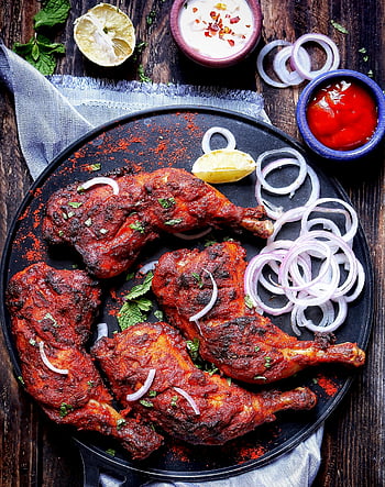 becue meat, round plate, onion rings, grilled chicken, spicy sauces, rustic platter, delicious food, lemon garnish, wooden table, tandoori chicken, dipping sauces