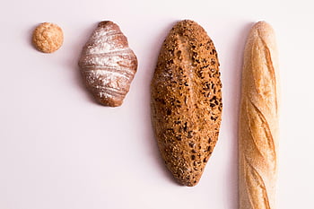 flatlay fotografie, různé druhy chleba, rohlík, bageta, nasazený bochník, Čistý bílý povrch, sortiment chleba, pekařské předměty, pečené dobroty, fotografování potravin, pohled shora
