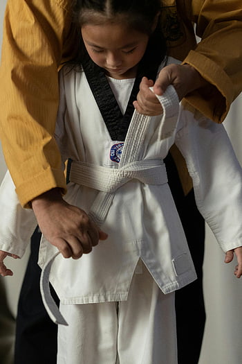 taekwondo, martial arts, belt tying, instructor assistance, child learning, martial arts belt, taekwondo uniform, martial arts training, child martial arts, instructor helping, martial arts practice
