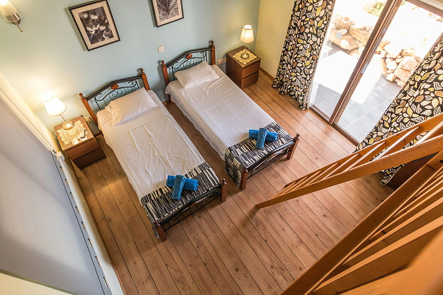 dvojčata, Rustikální ložnice, Dřevěný dekor, balkon, letecký pohled, Twin Bed Room, dřevěná podlaha, lůžkové lampy, zarámované obrázky, rustikální interiér, žebřík vedle postelí