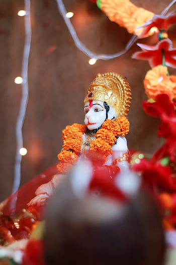 Hanuman, God figure, colorful idol, marigold garlands, Hindu worship, India, close-up, religious statue, cultural icon, spiritual symbol, traditional decoration