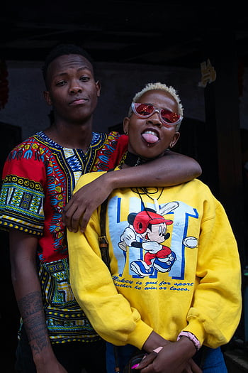 afrikansk amerikansk par, urban mode, Levende tøj, legende positur, stilfuld duo, Mickey Mouse sweatshirt, farverige outfit, bymæssige omgivelser, ungt par, væg baggrund, mode erklæring