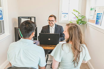 couple buying home, real estate agent, new home purchase, bright modern office, home buying consultation, couple consultation, real estate meeting, home buyers, modern office setting, real estate office, couple discussing home