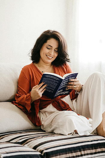livre de lecture femme, loisir intérieur, canapé, Dale Carnegie, vêtements confortables, décor, environnement domestique, lecture décontractée, couverture de livre, femme souriante, atmosphère confortable