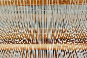 wooden loom, yarn threads, traditional loom, fine threads, wooden sticks, weaving process, textile production, detailed view, neat arrangement, craftwork, textile art