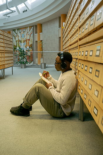 書く人、 ノート、 床に座って、 としょうかん、 ヘッドホン、 勉強する、 図書館の男性、 ノートブックに書く、 図書館の床、 ヘッドフォンを持った男、 図書館で勉強する