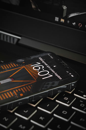 Handy, Laptop-Tastatur, Smartphone, Zeitanzeige, 16:01, Tech Setup, Geräteplatzierung, Moderne Technologie, Arbeitstisch, Digitaluhr, elektronische Geräte