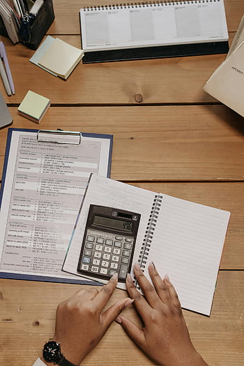 top view, person sitting, table, documents, calculator, office desk, sticky notes, hands using calculator, financial documents, workspace, office supplies