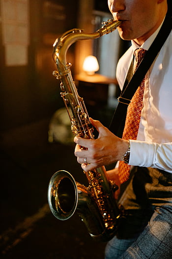 man playing saxophone, white long sleeve shirt, necktie, indoor jazz atmosphere, intimate setting, saxophonist, musical performance, formal attire, indoor music session, jazz musician, saxophone player