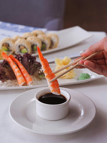 Garnelen-Sushi, Sojasauce, Essstäbchen, japanische Küche, Nahansicht, Sushi Rollen, Wasabi, Ingwer, Esstisch, weiße Platte, Handhalt des Stämchens