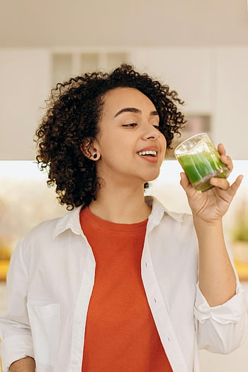donna che beve, frullato fresco, capelli ricci, donna sorridente, frullato verde, uno stile di vita sano, in casa, godersi il frullato, bevanda salutare, bevanda naturale, Smoothie vibrante