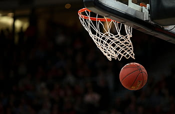 basketball hoop, basketball court, basketball game, fast-paced game, ball through hoop, sports excitement, basketball action, net, indoor sports, sports photography, game moment