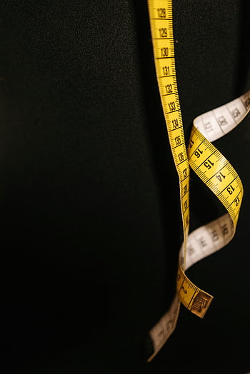 measuring tape, centimeter details, yellow measuring tape, black fabric backdrop, tailoring themes, close-up photo, centimeter measurements, tailoring tools, sewing accessories, fabric measurement, yellow tape measure