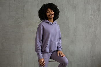 Usmívající se černošská žena, mikina s kapucí, vysoká židle, Veselá mladá žena, ležérní fialový outfit, sedí uvnitř, afro vlasy, fialová mikina, fialové oblečení, vnitřní portrét, Ležérní styl