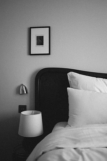 black and white bedroom, stylish bedroom decor, elegant bed, modern bedroom, black headboard, white bedding, minimalist bedroom, wall art, bedside lamp, contemporary bedroom, monochrome interior