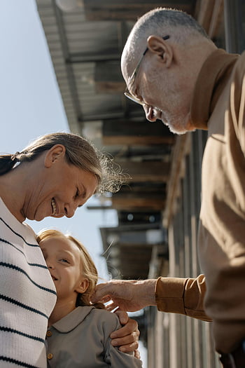 elderly couple, hugging, granddaughter, heartwarming moment, grandparents, joyful hug, smiling granddaughter, outdoors, family bond, intergenerational love, affectionate embrace