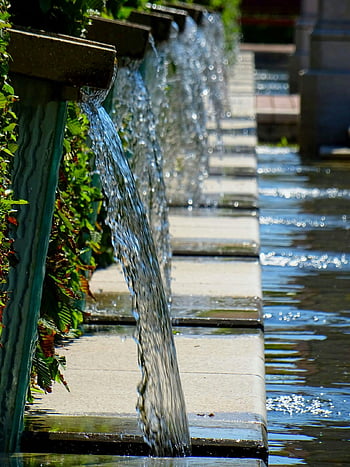 outdoor water fountain, green leafed plant, aesthetic garden fountain, cascading water, serene atmosphere, multiple streams, garden feature, outdoor decor, water feature, garden design, natural beauty
