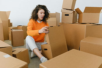 überraschte junge Frau, Öffnen eines Kartons, Paketzustellung, Boxen auspacken, neues Zuhause, Verpackungsmaterialien, Kartons, begeisterte Frau, einziehen, umgebende Boxen, Karton auspacken