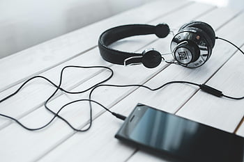 cuffie vintage nere, smartphone mobile, scrivania in legno leggera, musica portatile, tecnologia, cuffie e smartphone, impostazione della scrivania, equipaggiamento audio, tecnologia moderna, ascolto di musica, Accessori tecnologici