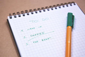 orange pen, green pen, graphing notepad, handwritten to-do list, graph paper notebook, organizing tasks, to-do list, task organization, pen on notebook, graph paper, spiral notebook
