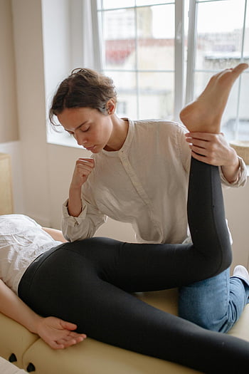 massage therapist, leg stretch, therapeutic care, indoor session, elbow pressure, client care, physical therapy, bodywork, health and wellness, professional massage, relaxation techniques