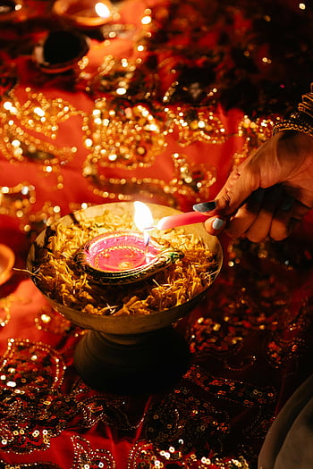 Diwali diya, lighting candle, vibrant decorations, traditional Diwali, close-up photo, festive lighting, cultural celebration, Indian festival, candle light, decorative diya, hand lighting