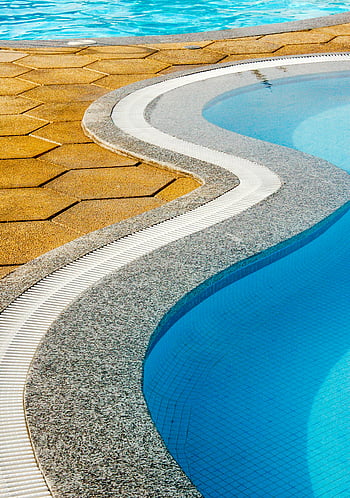 swimming pool, pool edge, curved edge, stone edge, tile edge, resort pool, close-up view, unique design, curved stone, pool design, blue water