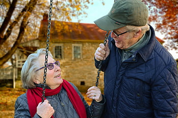 elderly couple, swing, autumn, joyful moment, man standing beside woman, happy couple, outdoor, fall season, elderly man, elderly woman, autumn leaves