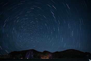 timelapse photography, stars at night, rotating star trails, mountainous landscape, night sky, mesmerizing, star trails, night photography, landscape photography, long exposure, celestial photography