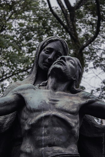 statue, low angle shot, religious themes, grief, spirituality, outdoor sculpture, nature, trees, powerful, bronze, pieta