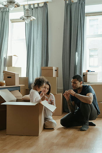 family moving, cardboard boxes, new home, man in blue polo shirt, woman in gray long sleeve shirt, moving process, organizing boxes, family enjoying move, new home setup, moving day, family activity